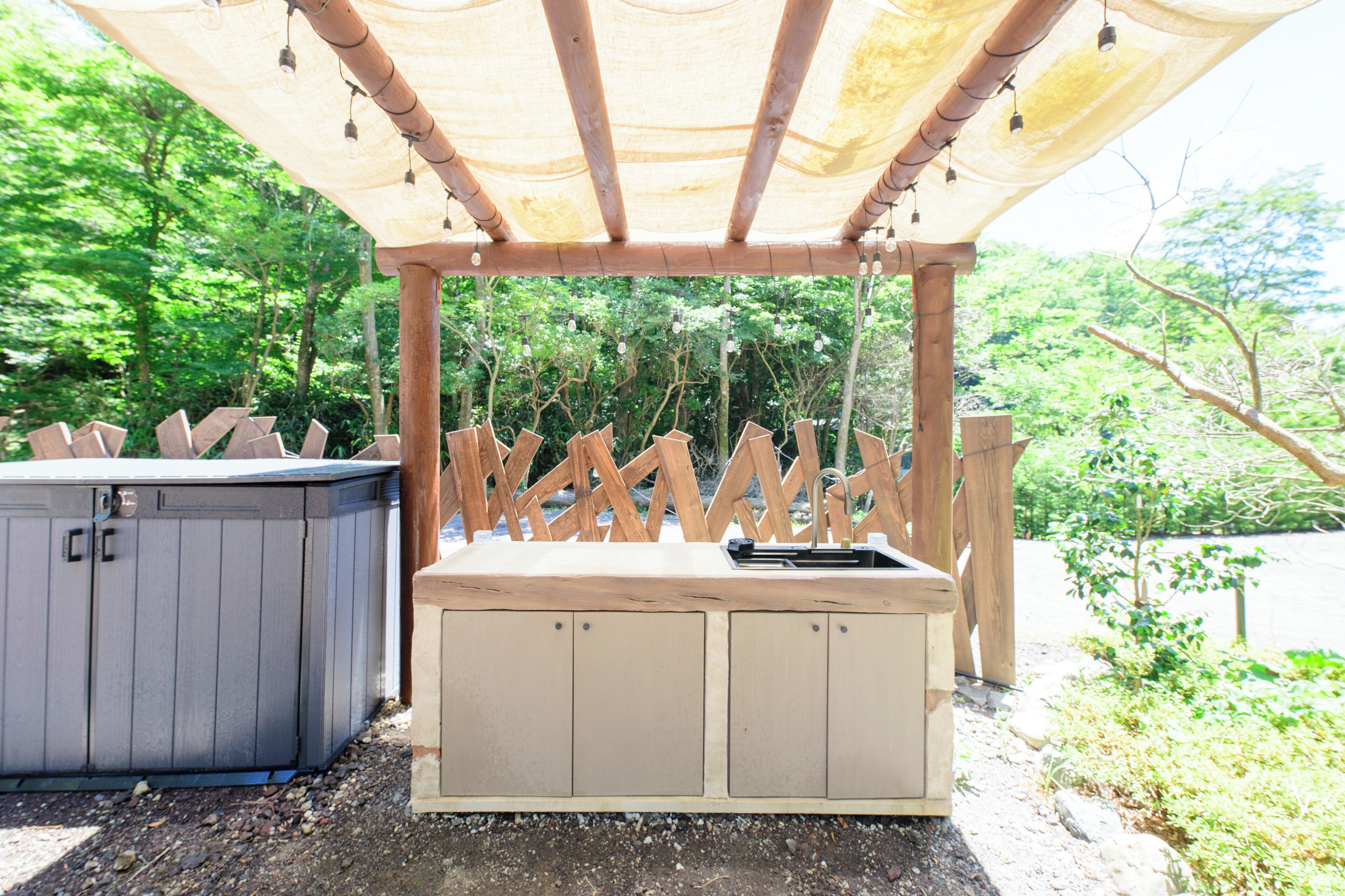 A wooden outdoor seating area with a bench and a hot tub.