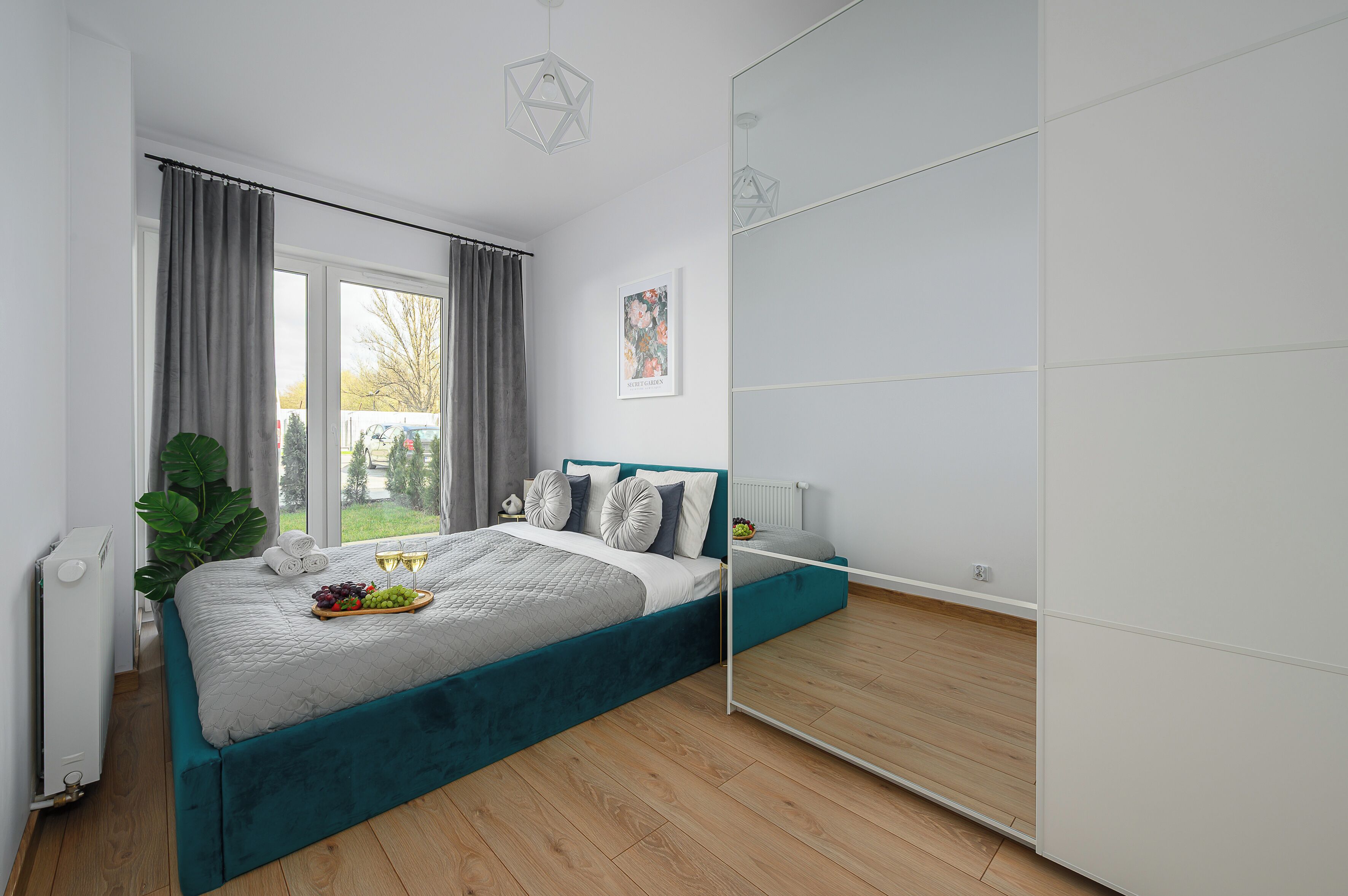 Ein modernes Schlafzimmer mit Bett, einem großen Spiegel und Blick ins Freie.