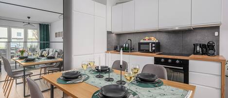 A modern kitchen with white cabinets, a wooden countertop, and a dining area with a table set for four.