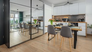 A modern kitchen with a dining area, large windows, and a view of the outdoors. - Lumina apartment with patio and parking (Łódź)