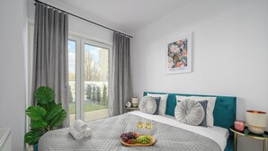 Une chambre à coucher comprenant un lit, une fenêtre, des rideaux, une plante, un tableau décoratif et une table de chevet avec une lampe.