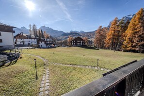 Eine Wiese mit Gebäuden und Bergen im Hintergrund.