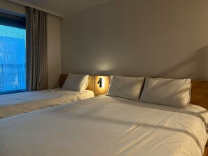 A hotel room with two beds, a large window with curtains, and a wall-mounted light. - JS building 403 (Seoul)