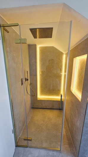 Box doccia moderno con porta in vetro, soffione integrato e luce a parete.