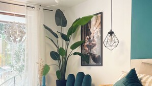 A bedroom with a striped bedspread, a large potted plant, a hanging light fixture, and a framed picture on the wall. - Cozy apartment near Lake Constance - ideal for couples (Friedrichshafen)