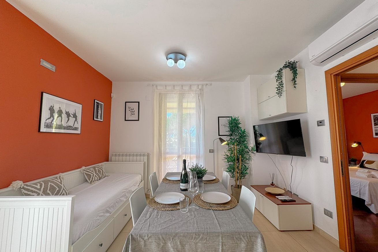 A modern living room with a sofa, dining table, TV, and a plant.