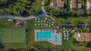 Ett flygbildsbild av ett bostadsområde med en swimmingpool, en tennisbana och flera hus.