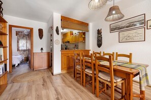 A dining area with wooden furniture, a woven rug, and wall-mounted artwork. - Casita Abrilcon with Garden (Cap Roig)