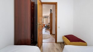A room with two beds, a wooden wardrobe, and a doorway leading to another room. - Casita Abrilcon with Garden (Cap Roig)