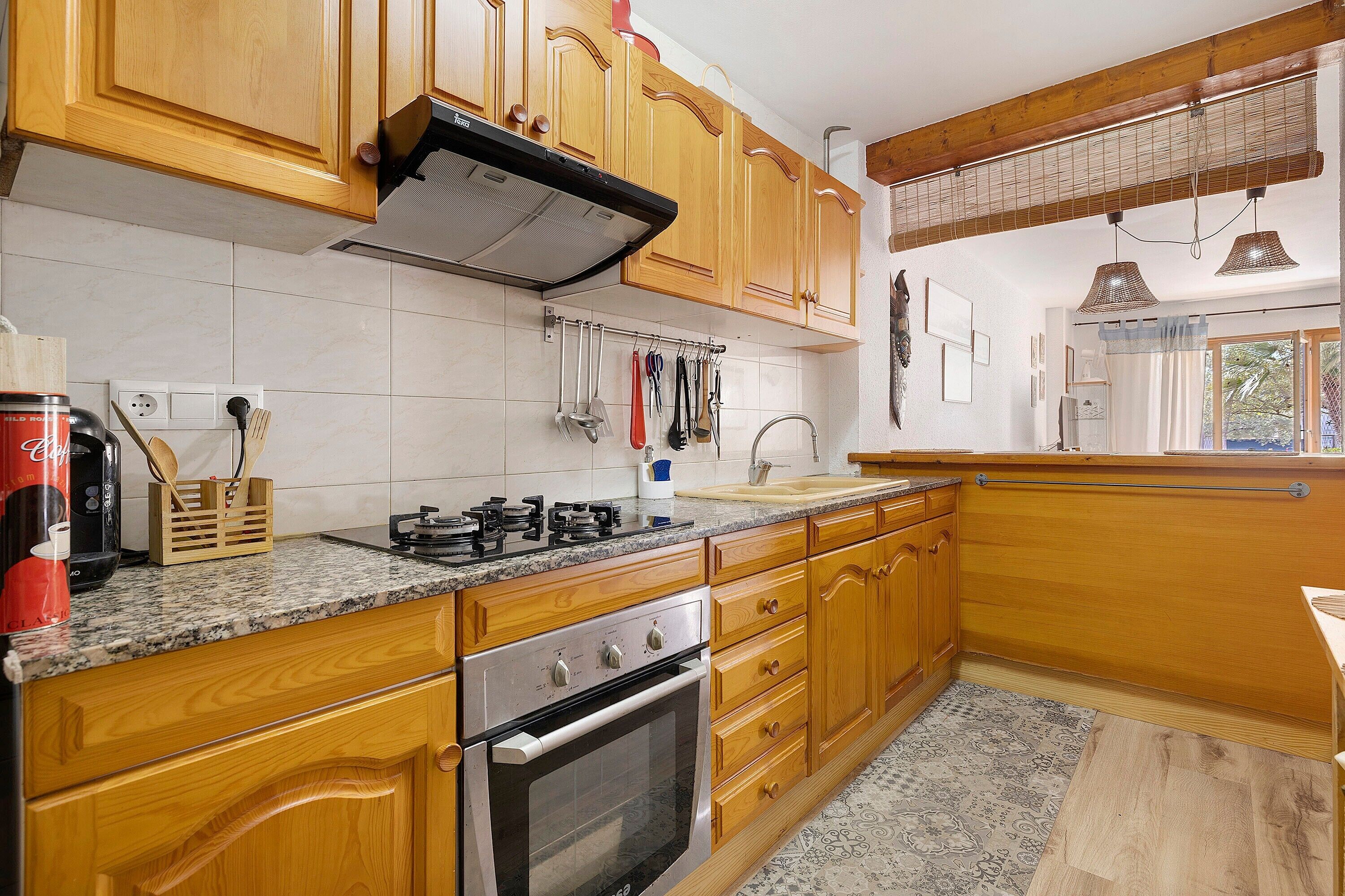 Une cuisine avec des meubles en bois, une cuisinière à gaz, un four et une fenêtre donnant sur un beau paysage.