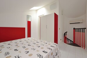 A bedroom with a bed, a wardrobe, a staircase, and an air conditioning unit. - Two level flat with balcony (Lignano Sabbiadoro)