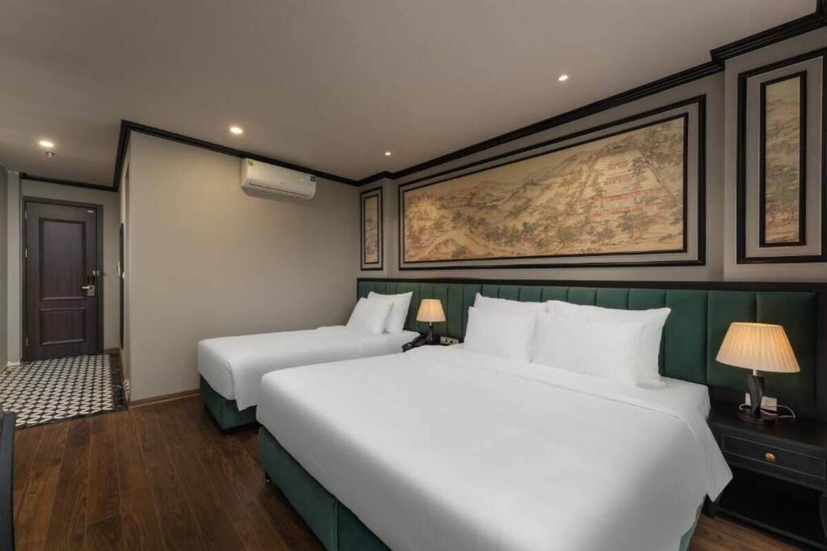 A hotel room with two beds, a large map on the wall, a wooden floor, and an air conditioning unit.
