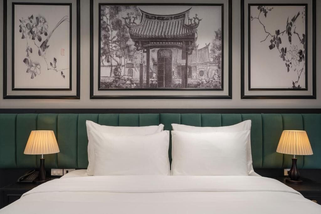 A bed with white linens, two bedside lamps, and framed artwork above.