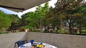 A balcony with a table set for breakfast, including bread, pastries, fruit, and beverages. - Quiet living for your vacation (Lignano Sabbiadoro)
