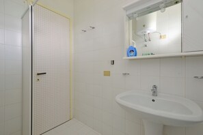 A bathroom with a shower, a sink, and a mirror. - Cozy stay in Lignano (Lignano Sabbiadoro)