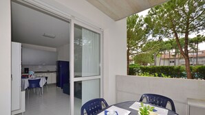 A dining area with a table, chairs, and a view of the kitchen and outside. - Cozy stay in Lignano (Lignano Sabbiadoro)