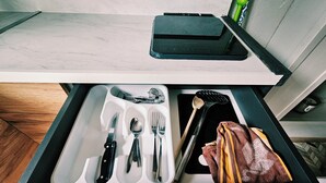 Uma gaveta com utensílios, um pano e um objeto preto.