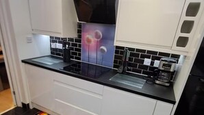 Une cuisine moderne avec des plans de travail noirs, des meubles blancs et un four à micro-ondes.