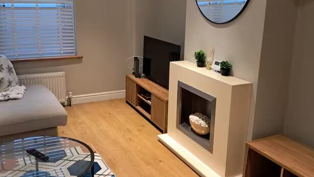 Un salon avec un canapé, un téléviseur, une cheminée et une table basse.