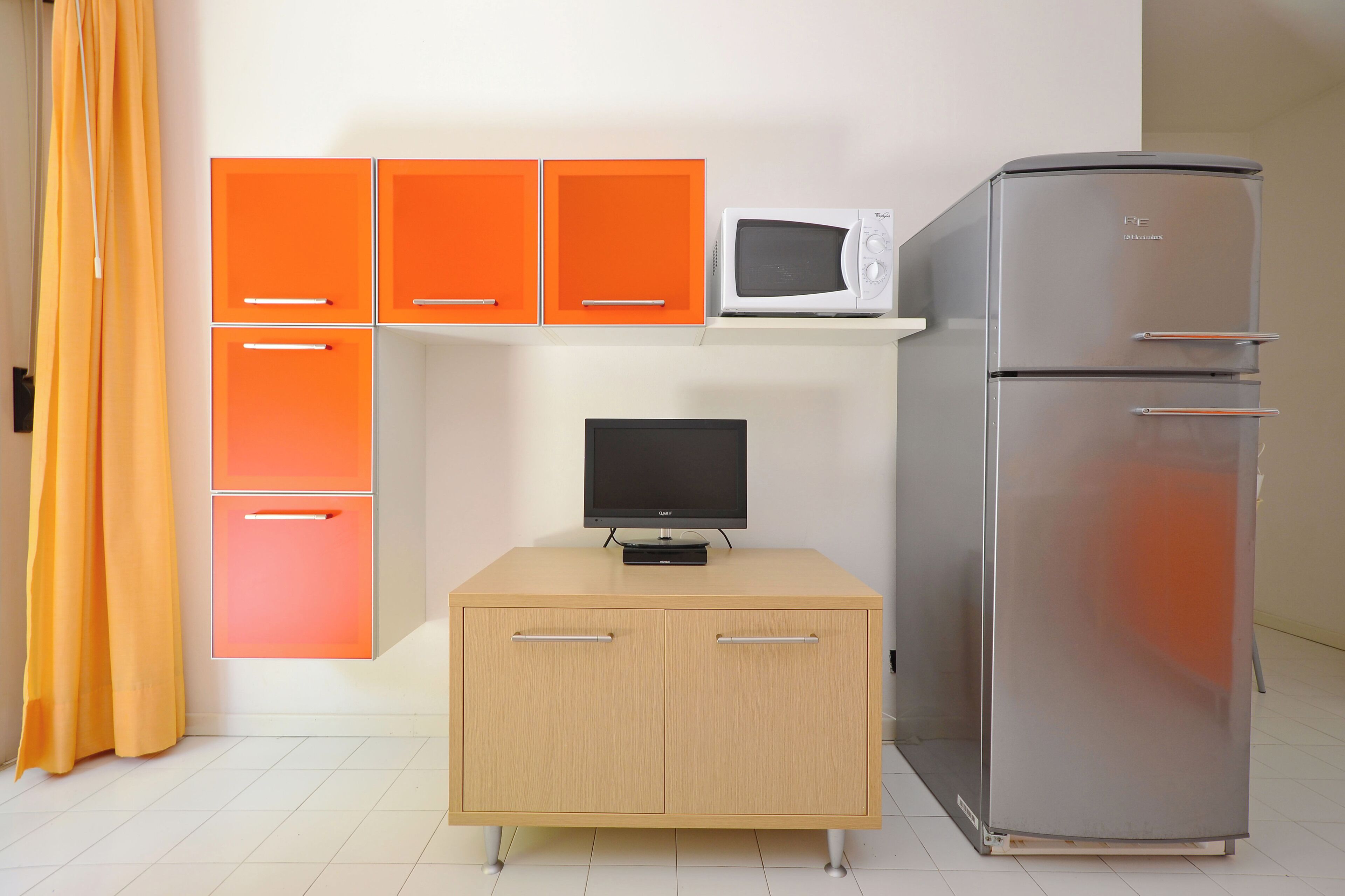A kitchenette with a microwave, refrigerator, and a small cabinet with drawers.
