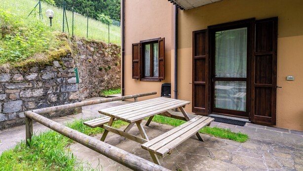 Eine Steinmauer, ein Holztisch und ein Gebäude mit Tür und Fenster.