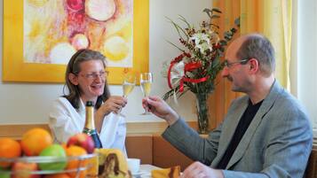 Ein Esstisch mit einer Obstschale, einer Flasche und einem Glas Champagner.