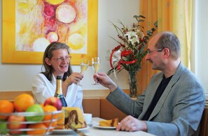 A dining table with a fruit bowl, a bottle, and a glass of champagne.