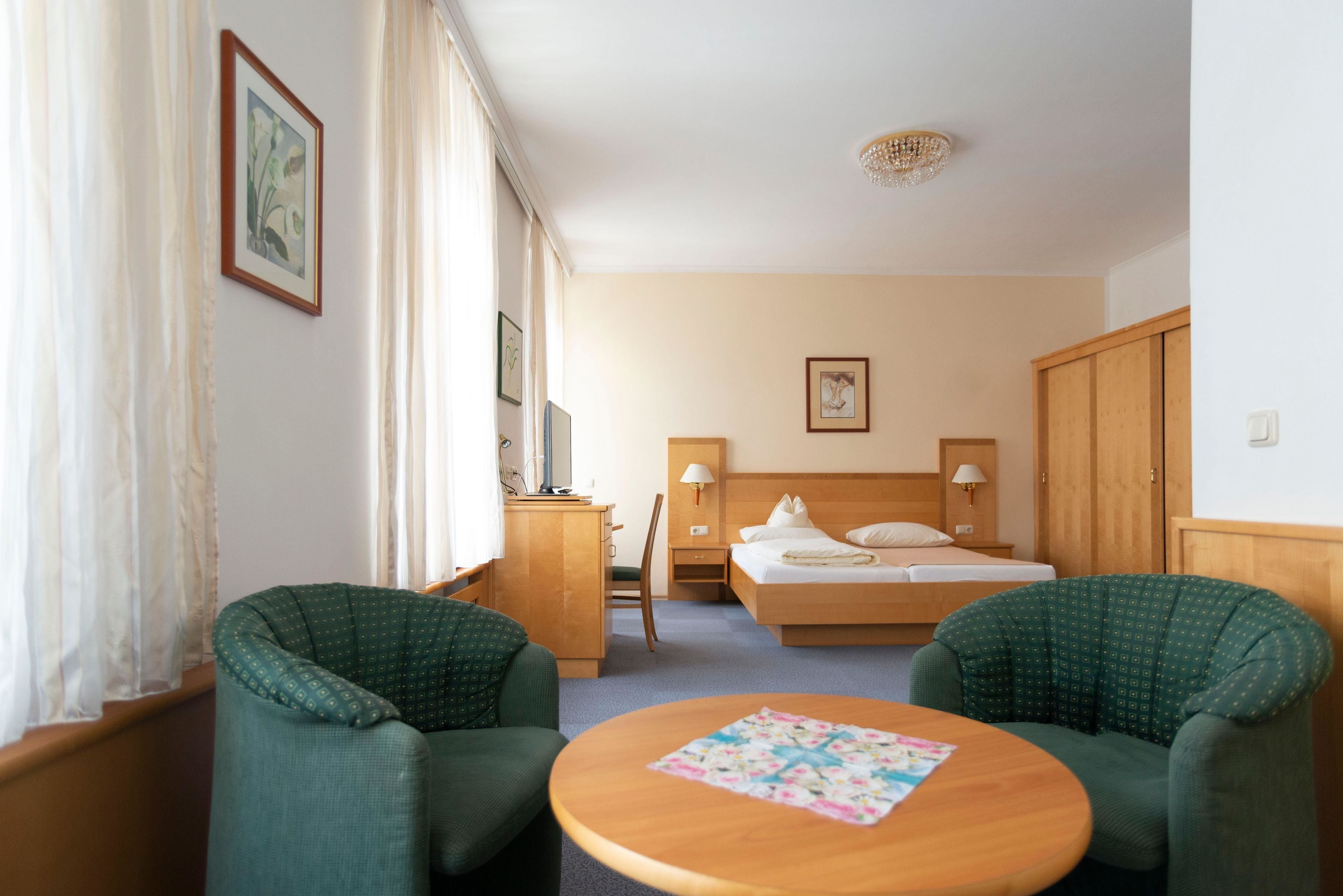 Una habitación de hotel con una cama, dos sillas, un escritorio y una mesa redonda.