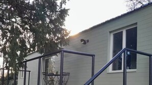 Et hus med træterrasse, gelænder i metal og et vindue.