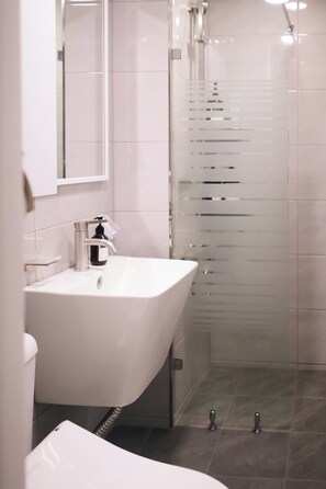 A modern bathroom with a white sink, a mirror, and a glass shower enclosure. - JS building-404 (Seoul)