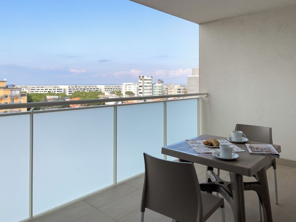 Ein Balkon mit Tisch für zwei Personen, einem Stuhl und Blick auf die Stadt.