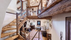 Eine mehrstufige Holztreppe verbindet verschiedene Räume, während ein Sofa, ein Tisch und ein Stuhl eine gemütliche Atmosphäre schaffen.