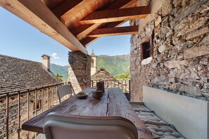 Una mesa de madera rústica con vistas a un edificio de piedra y montañas al fondo.