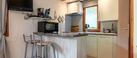 A kitchen with a built-in microwave, a coffee maker, and a wooden bar stool.