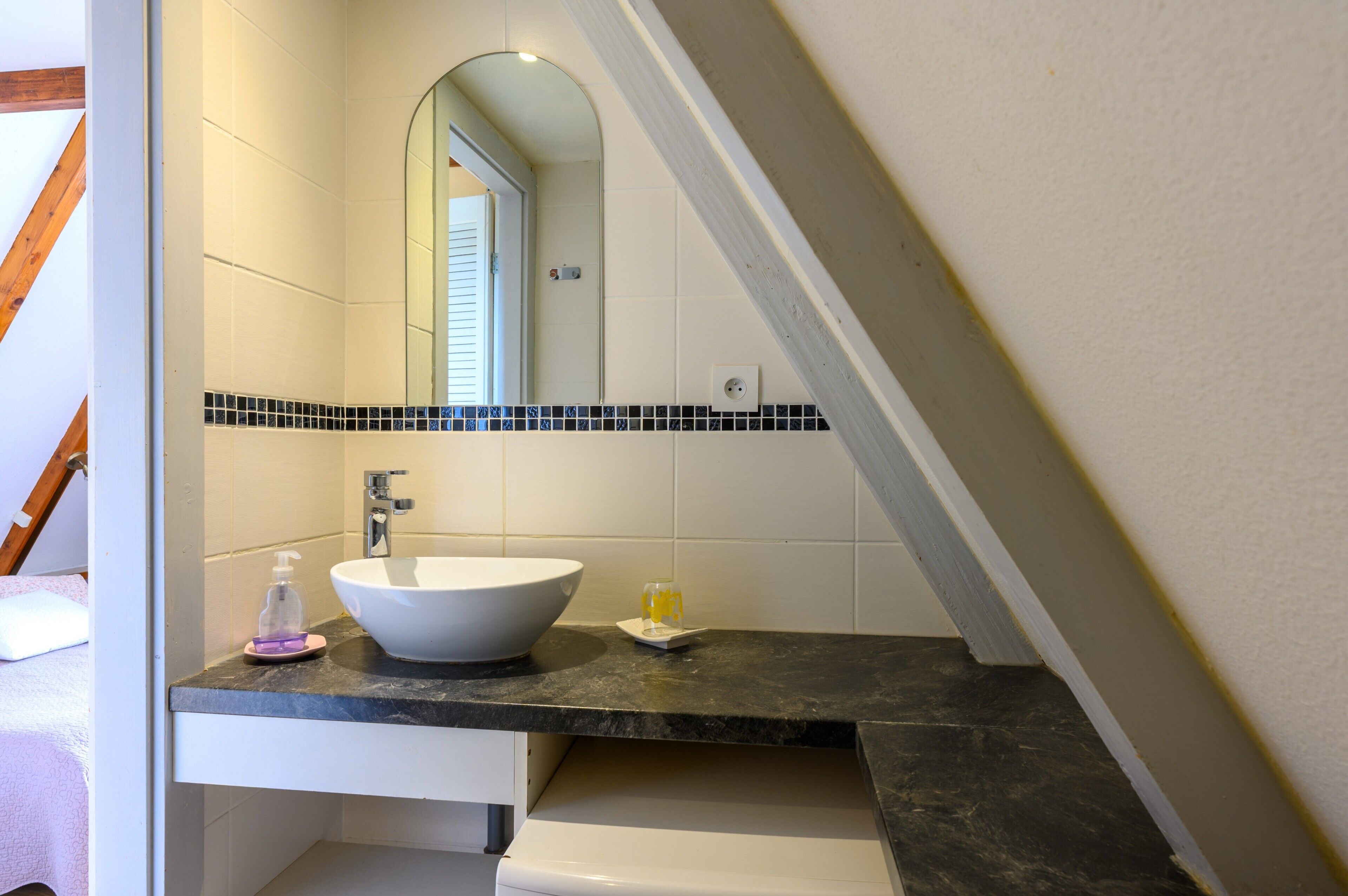 A bathroom with a white sink, black countertop, and a mirror above it.