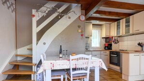 Eine Küche mit Esstisch, Stühlen, einer Uhr und einer Treppe.