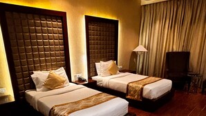 Une chambre d’hôtel avec deux lits, un plancher en bois, un ventilateur de plafond et une lampe.