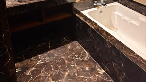 Une salle de bain avec un meuble-lavabo en marbre, une baignoire et un miroir.