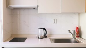 Une cuisine équipée d’une cuisinière intégrée, d’une cafetière en verre, d’un évier et d’un extincteur.