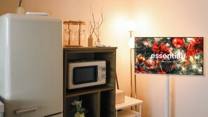 Une cuisine équipée d’un réfrigérateur, d’un four à micro-ondes et d’un téléviseur diffusant une décoration de Noël.