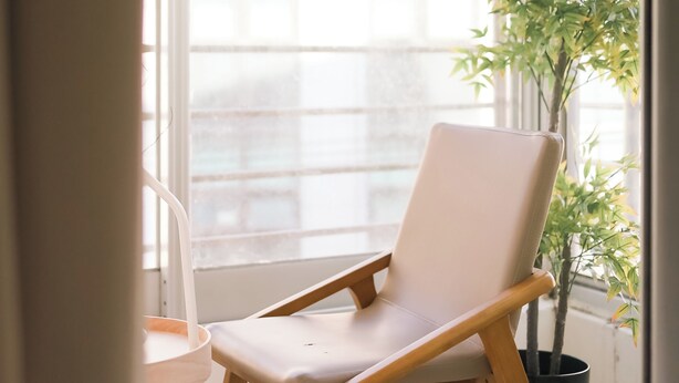 Un balcon avec une chaise, un pot de fleurs et une suspension lumineuse.