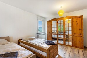 Un dormitorio con cama de madera, una ventana y un armario con puertas de cristal.