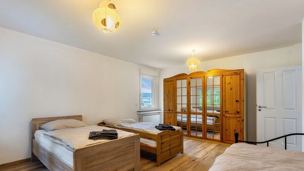 Een slaapkamer met twee houten bedden, een kledingkast en een raam met uitzicht.