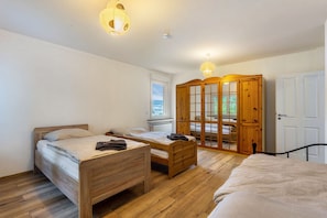 A bedroom with two wooden beds, a wardrobe, and a window with a view.
