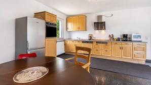 Een moderne keuken met houten kastjes, roestvrijstalen apparatuur en een eethoek met een tafel en stoel.