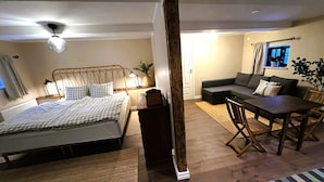 Een slaapkamer met een bed, nachtkastje, lamp en een raam.