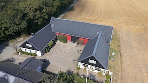 Luchtbeeld van een boerderij met twee schuren, een verharde oprit en omliggende velden.