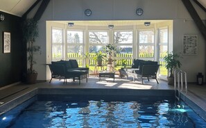 Un espace piscine donnant sur une terrasse en bois et une cour clôturée.