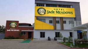 A hotel with a prominent yellow and green sign, a modern building facade, and a paved entrance area.
