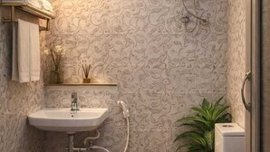 A bathroom with a white sink, toilet, and a water heater. There is a towel rack with folded towels, a small plant, and a brown rug on the floor.